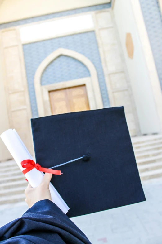 person holding a diploma in front of a church