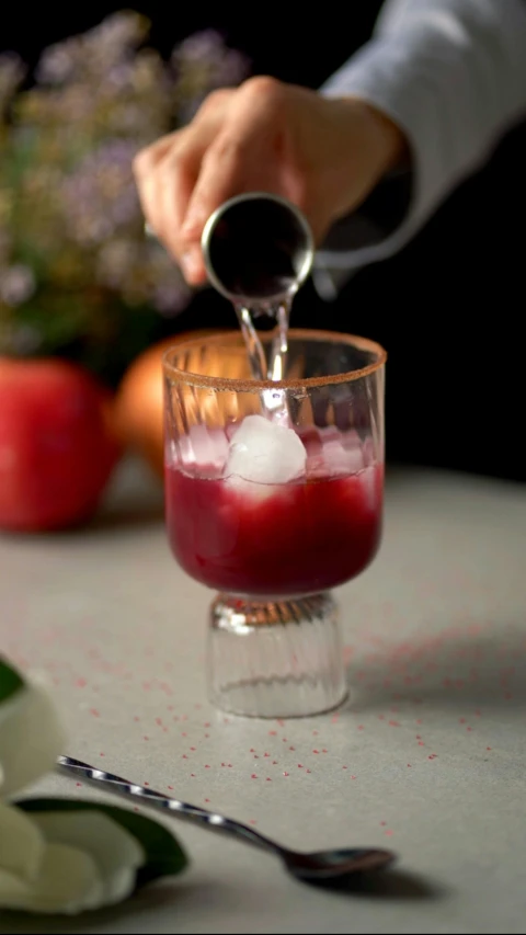 someone putting an ice in a glass full of some sort