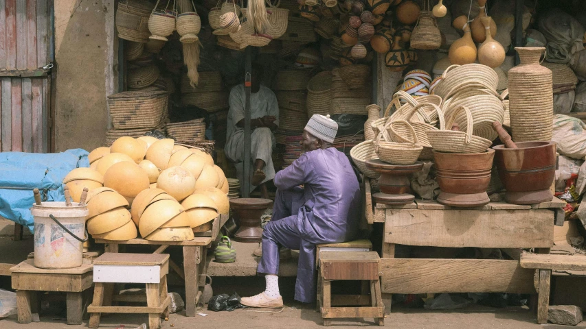 the man is seated near piles of fruit