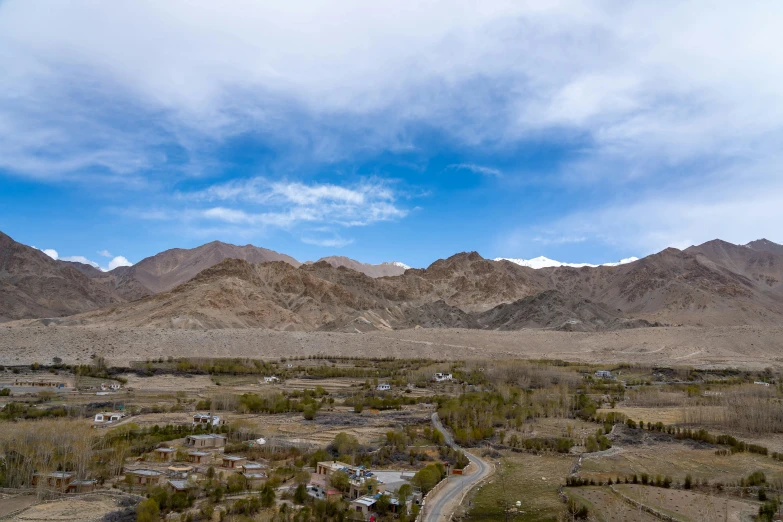 a road going through an arid land with hills in the background