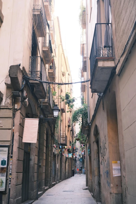 a narrow city alleyway with balconies on the second story