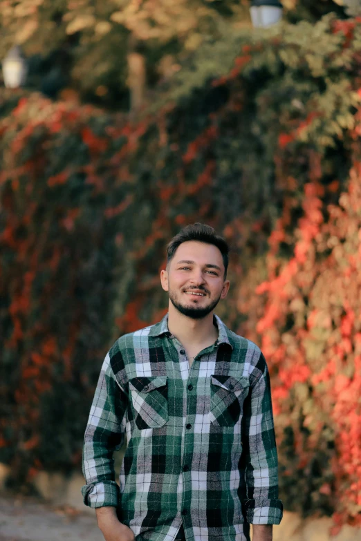 a man smiling while standing near an orange tree