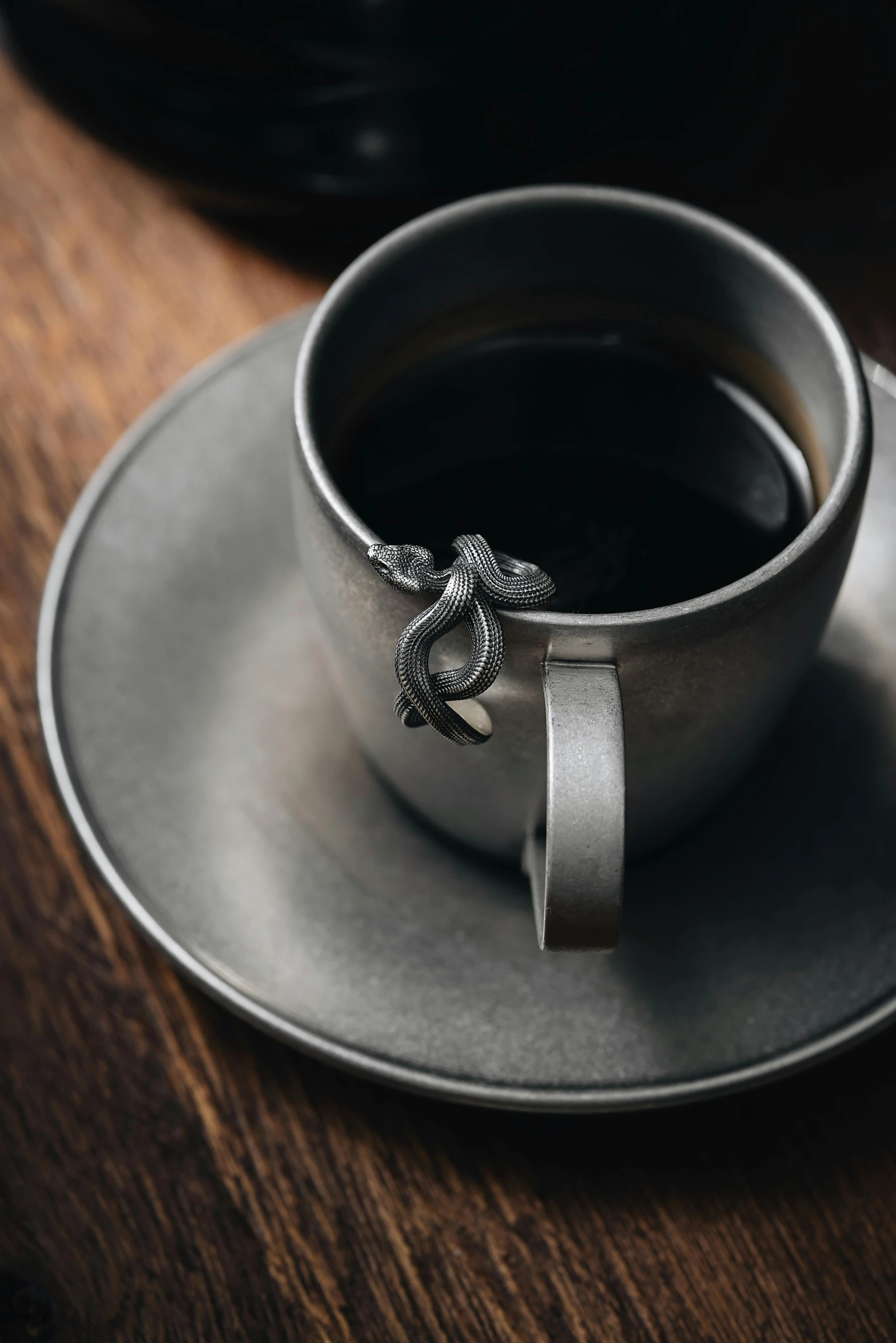 a cup of black coffee with a snake ring