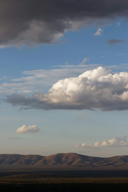 large clouds loom over rolling hills on a cloudy day