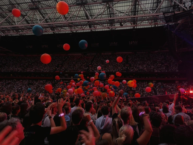 an audience at a concert holding up balloons