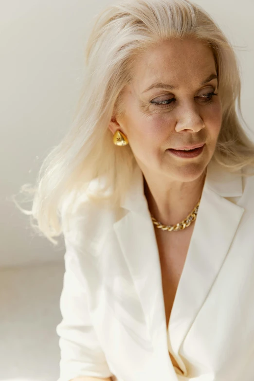 a woman in white shirt and necklace looking off