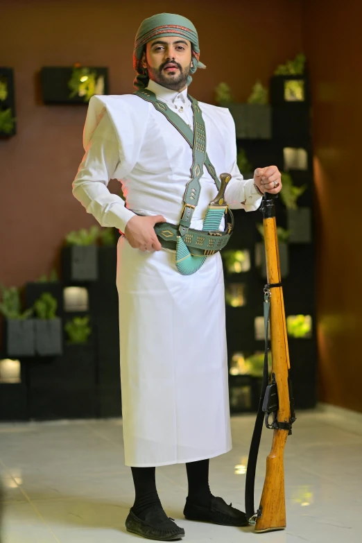 a man standing wearing white clothing holding a wooden toy gun