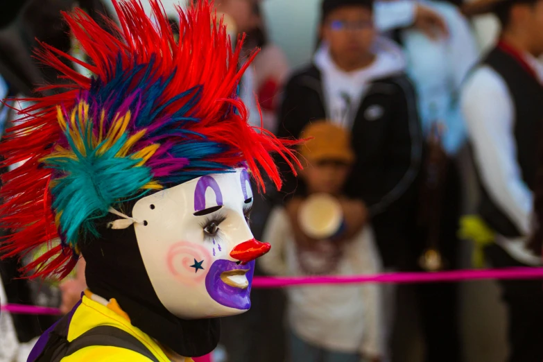 a face painted clown is next to a crowd