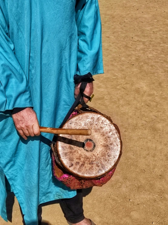 a man in blue holding a brown and silver drum