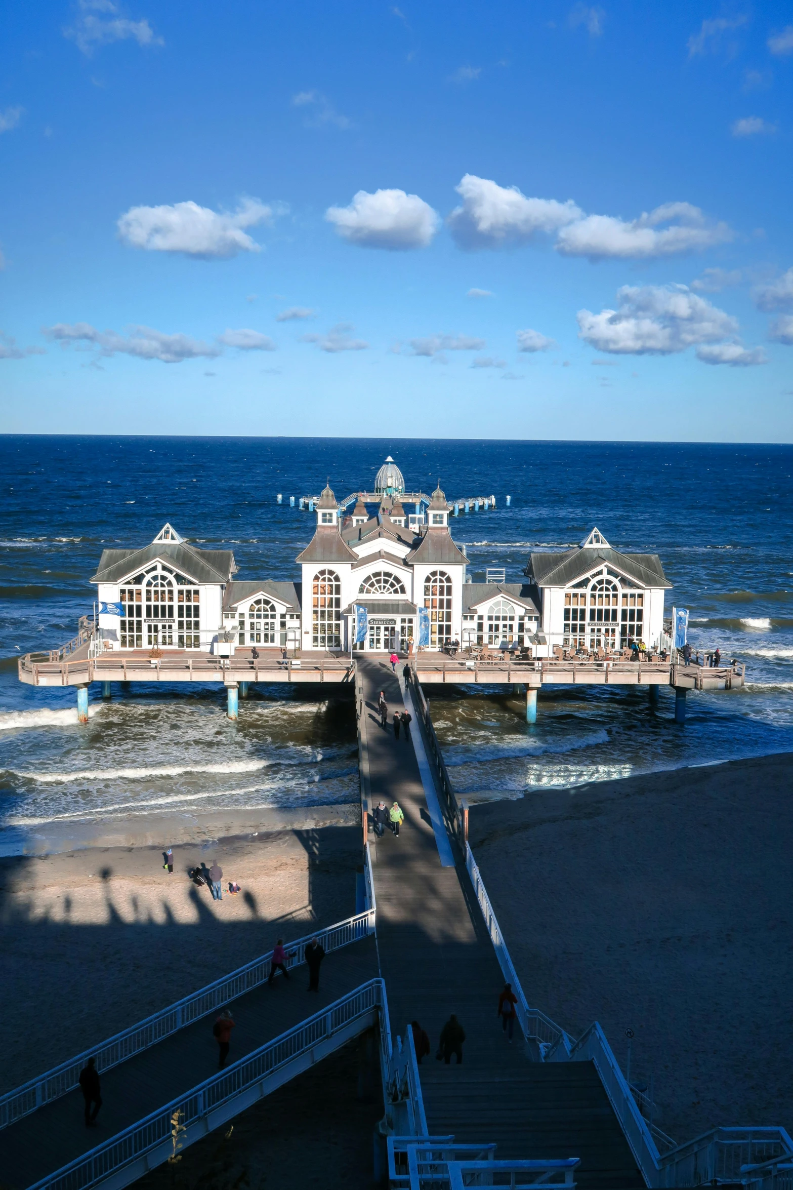 a pier in the ocean with people walking around it