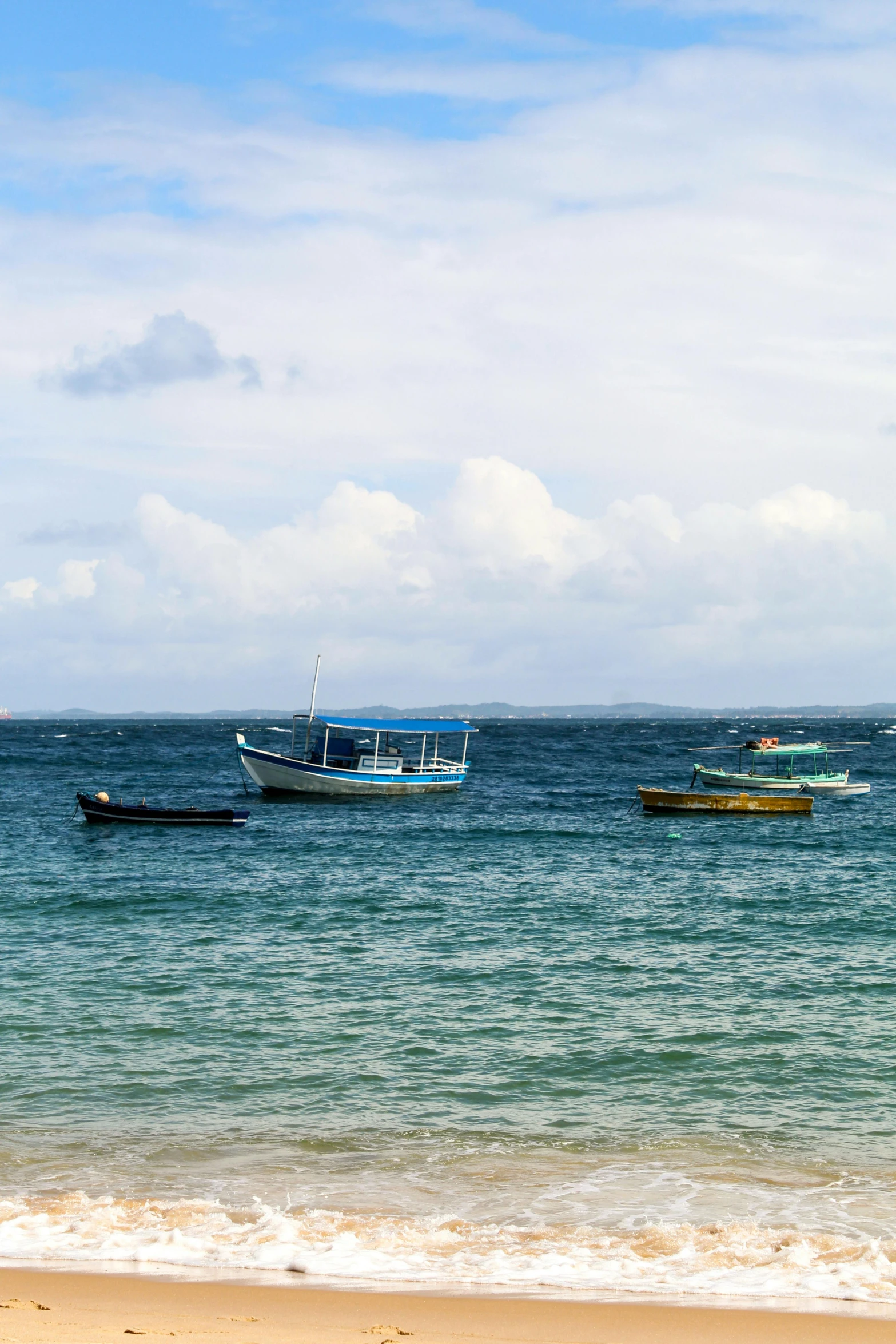 a group of boats floating in the ocean on a cloudy day