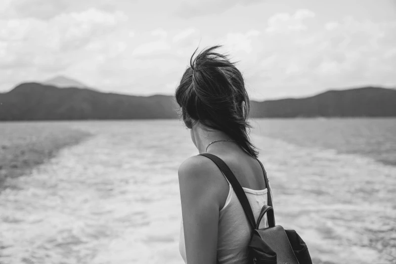 a woman in a tank top standing next to the edge of a body of water