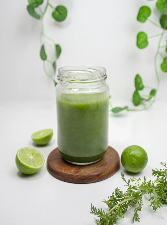 limes and green stuff sit beside a glass jar