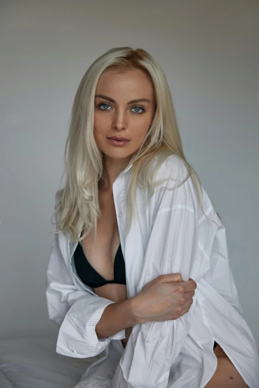 a young blonde is posing in a white shirt