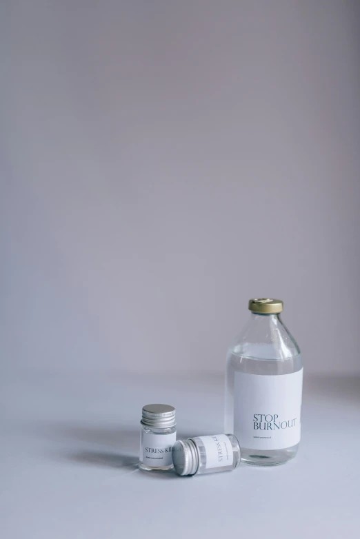 three empty bottles with silver caps are sitting in a studio setting