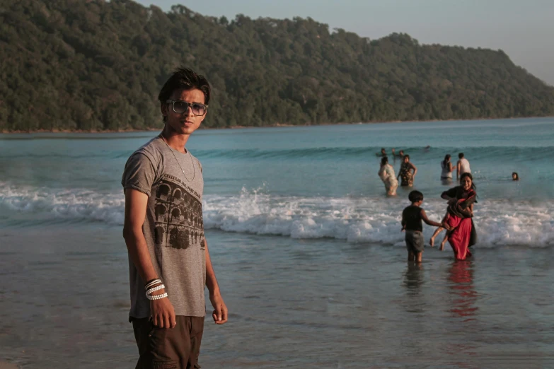 a man in sunglasses is standing in the water by some people at a beach