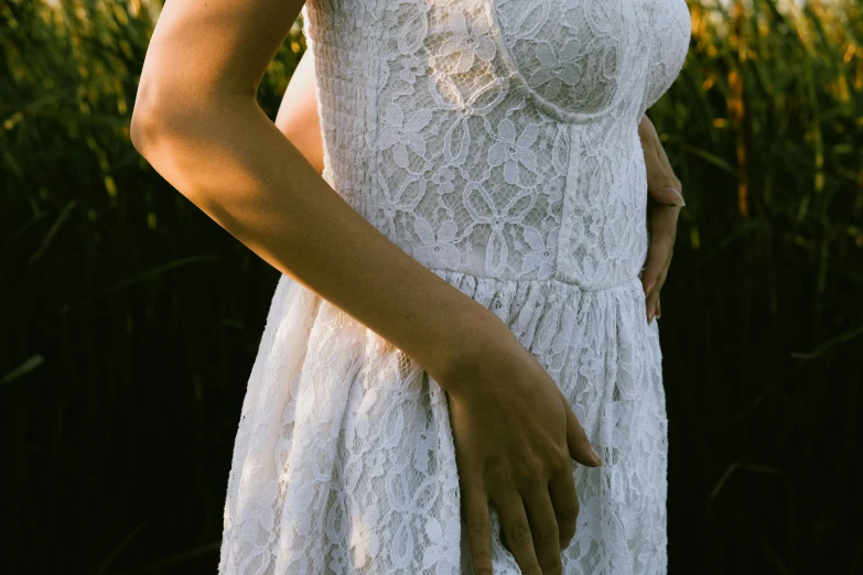 a woman is wearing white lace dress with her hands on her hip