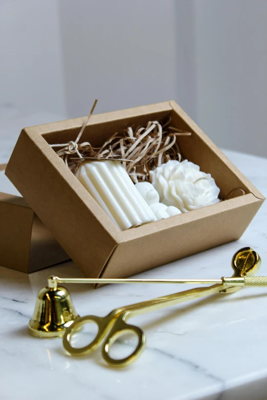 two small candles, a pair of gold scissors and white flowers