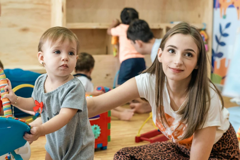 young child helping mother holding up a wooden toy