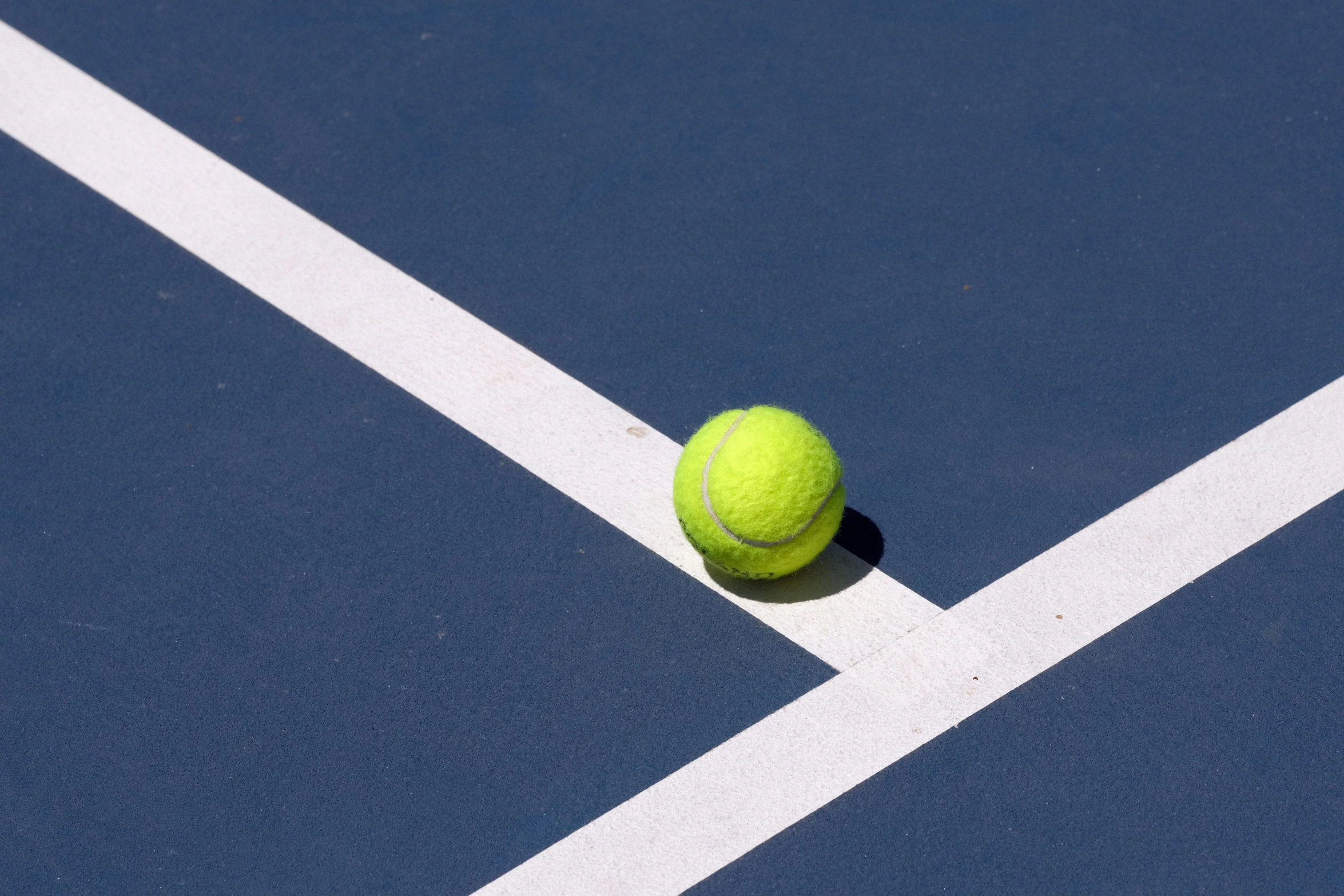 a tennis ball lays on a blue tennis court