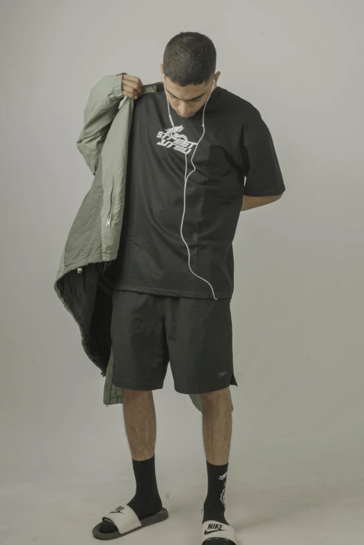 a man with ear buds holding a jacket