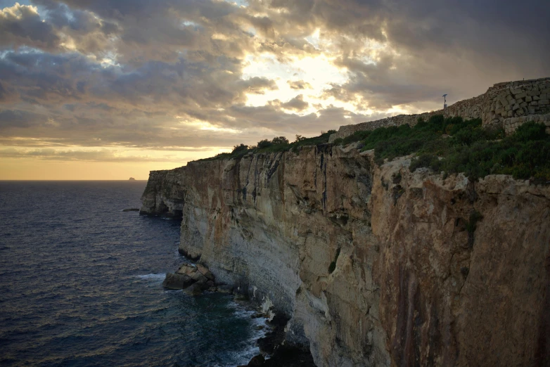 large rock formation with some water and clouds on it