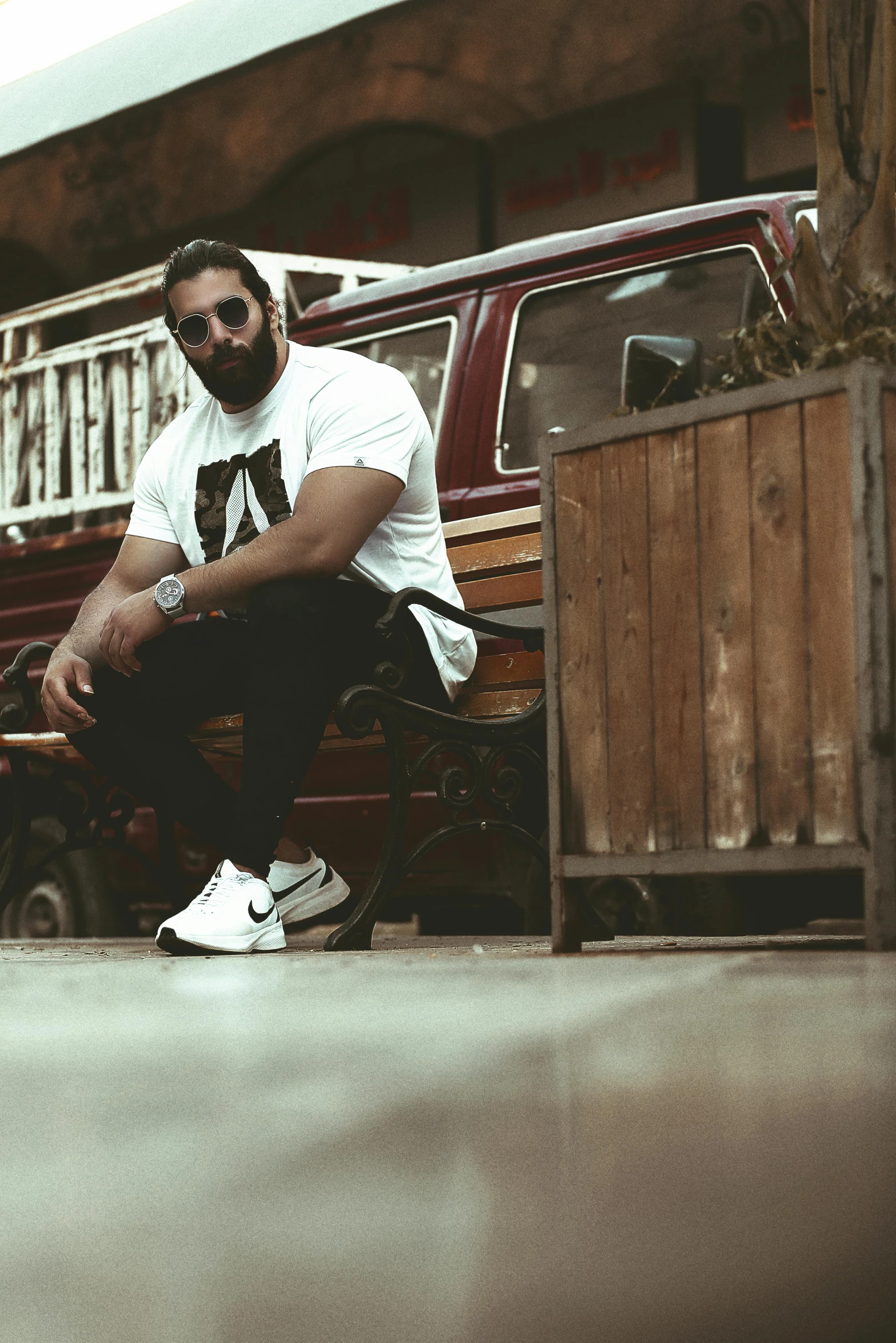 a person sitting on a bench in front of a red van