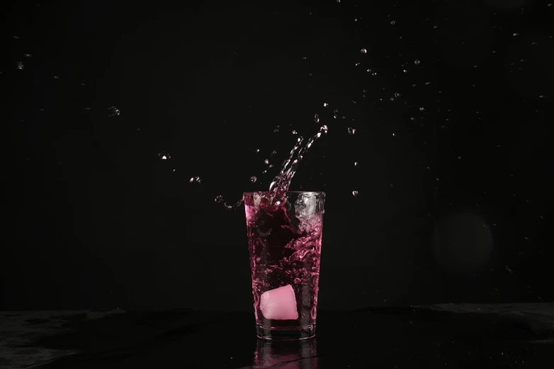 splashes and bubbles falling into a purple drink in front of black background