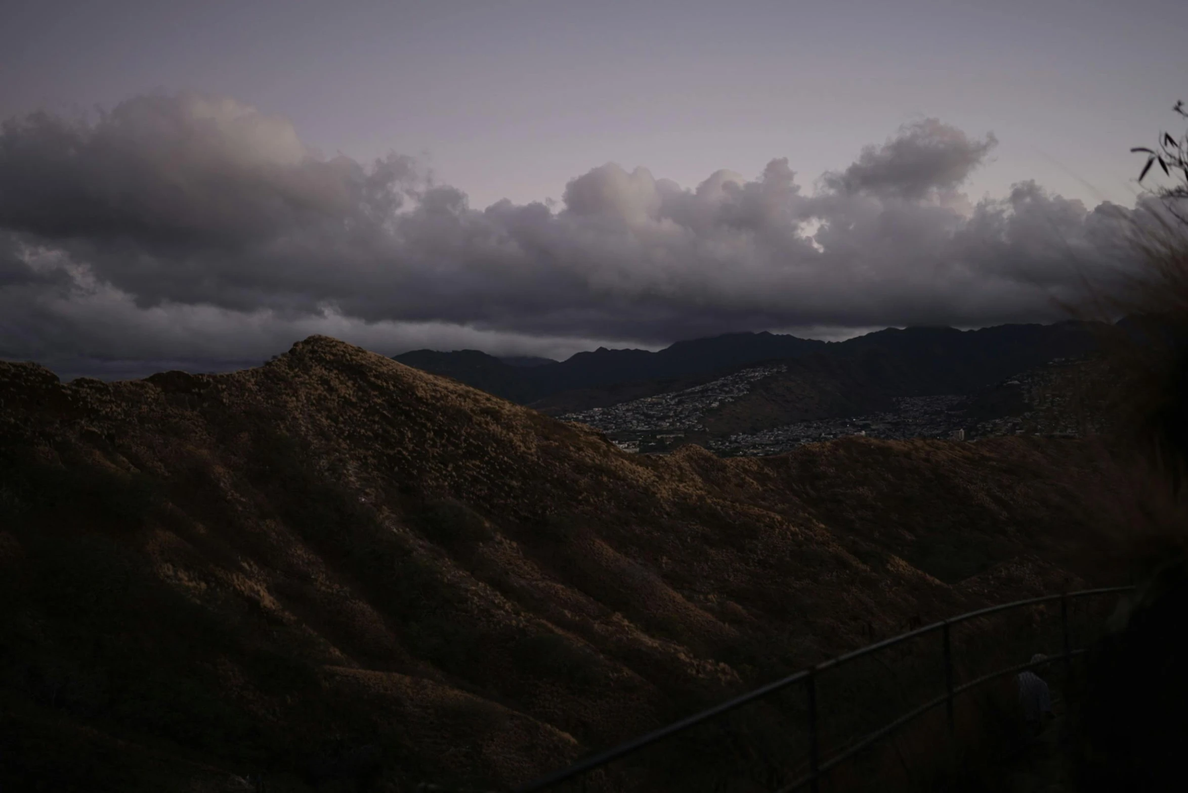 a landscape po with dark clouds and a hill behind it