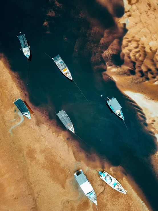 four small boats in the water, with dark brown sand