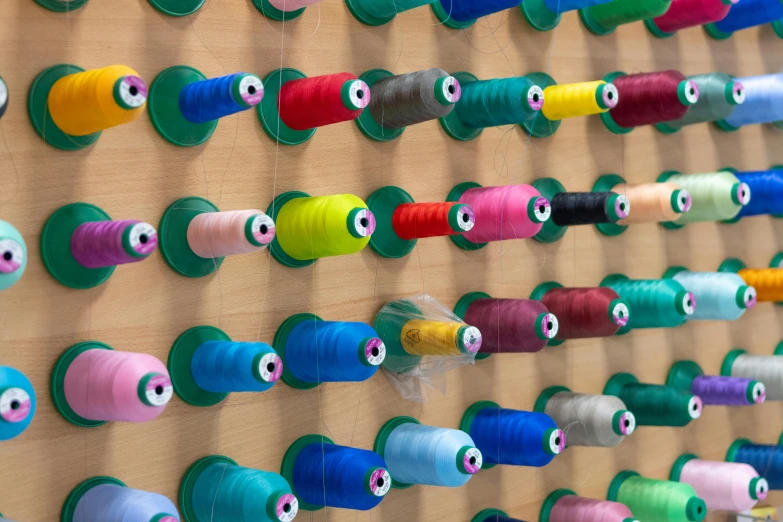 different colored spools of thread hang on the wall