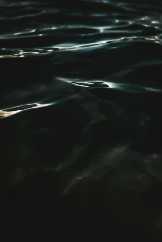 a dark po of ocean water with the reflection of clouds on it