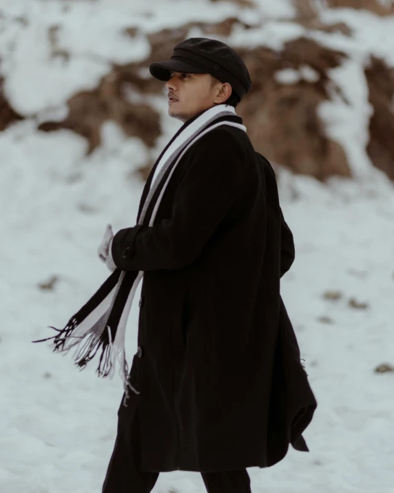 an older man with hat and scarf walks on the snow