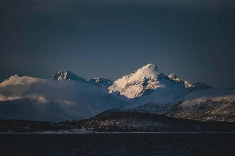 mountains with some trees in the foreground are covered by snow