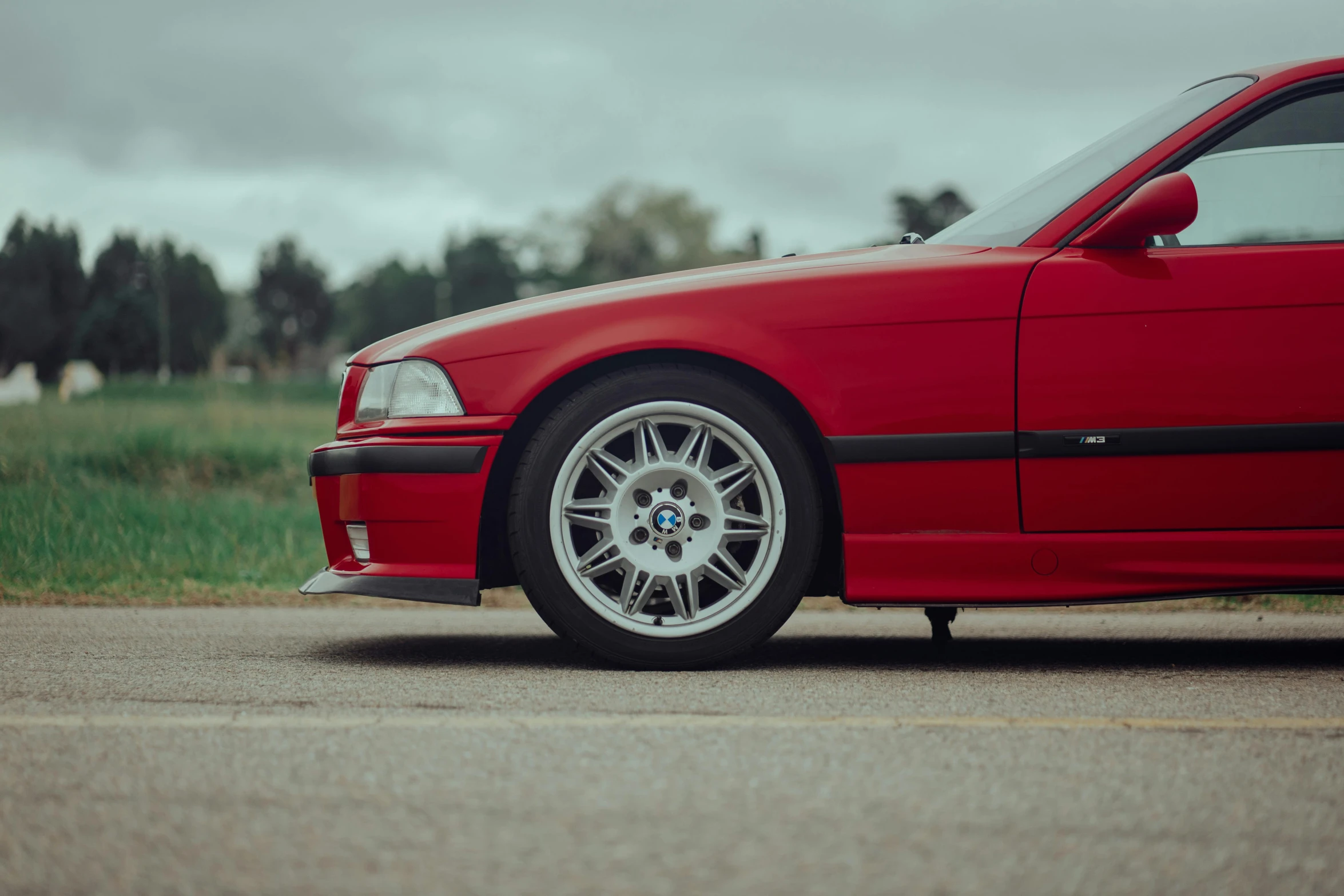 a red bmw sports car sitting on the side of a road