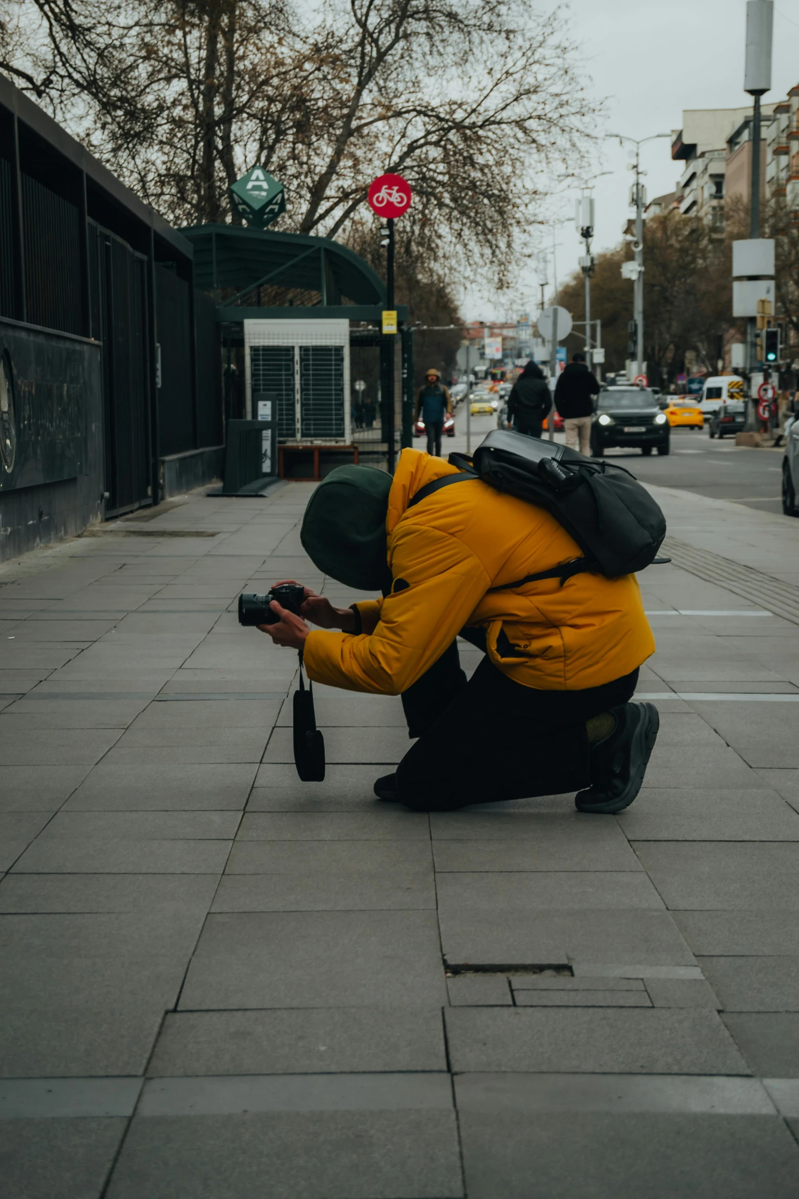 the man crouches down to take pictures of a street corner