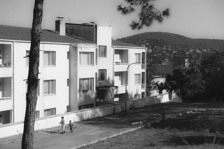 two children playing on the sidewalk near a large white building