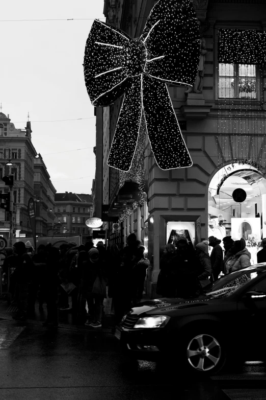 a group of people standing outside of a building under a lit umbrella