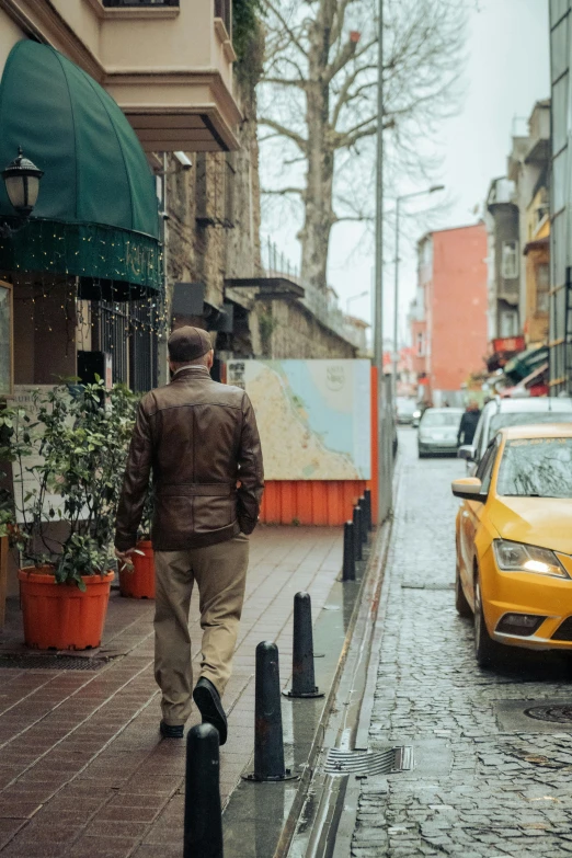 a man walking down a rain soaked sidewalk