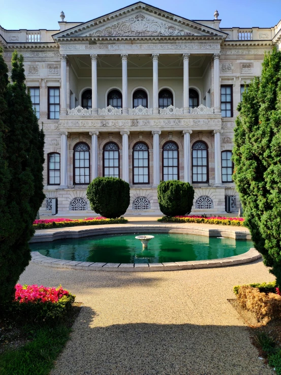 a tall white building with many windows and a fountain in front of it