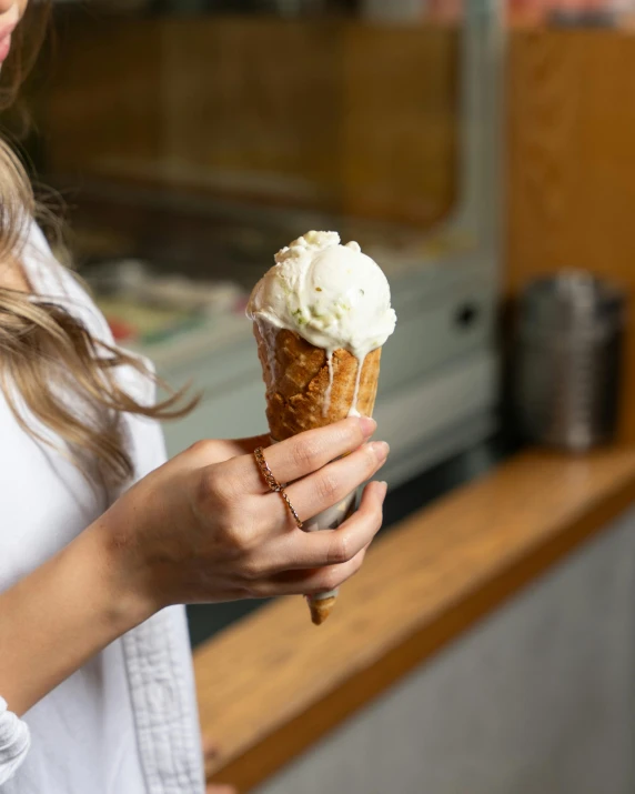 woman eating an ice cream cone sitting on top of a counter