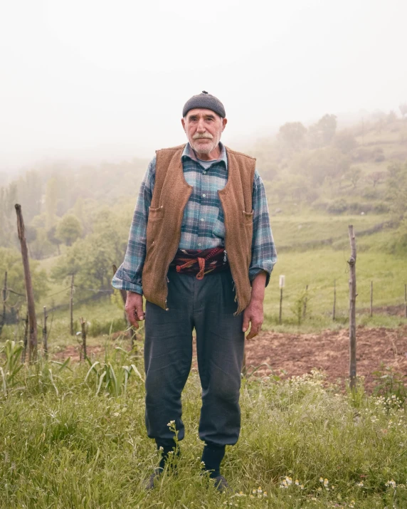 a man stands in a foggy pasture on his farm