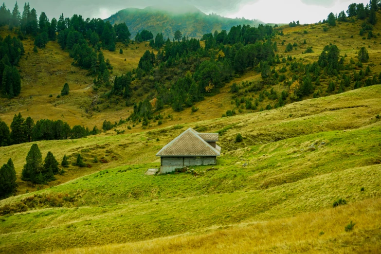 a small shack sitting on top of a grass covered hillside