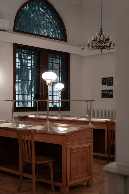 a wood desk with multiple chairs and a lamp