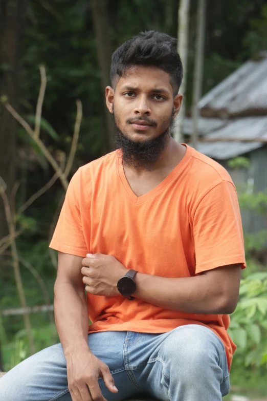 man sitting on ledge of outdoor area with fence and trees