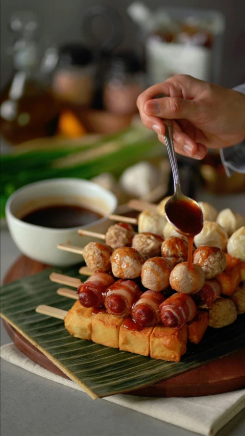 sausage covered with meatballs on skewers on a banana leaf