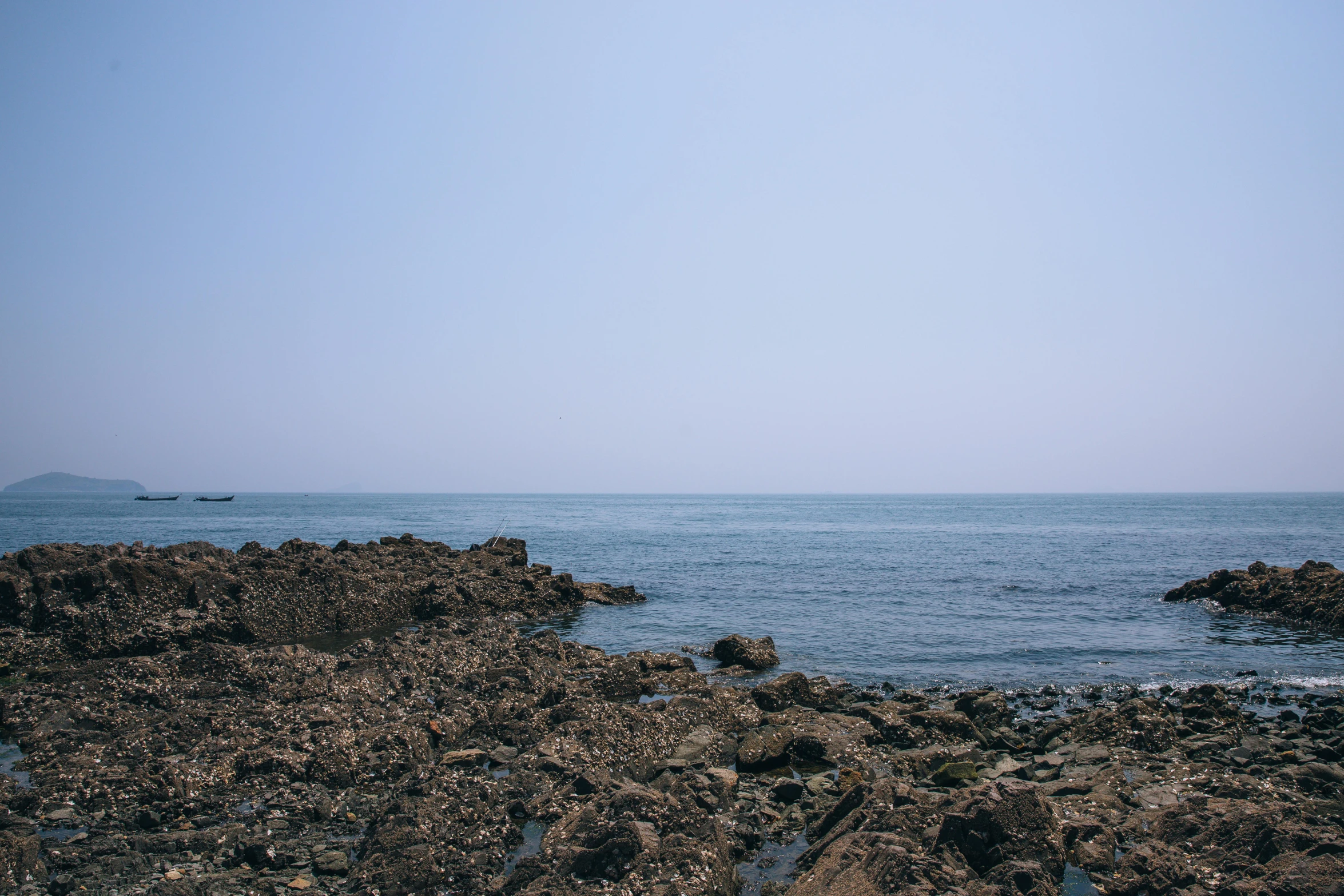 ocean scene with rocky shoreline and distant boat