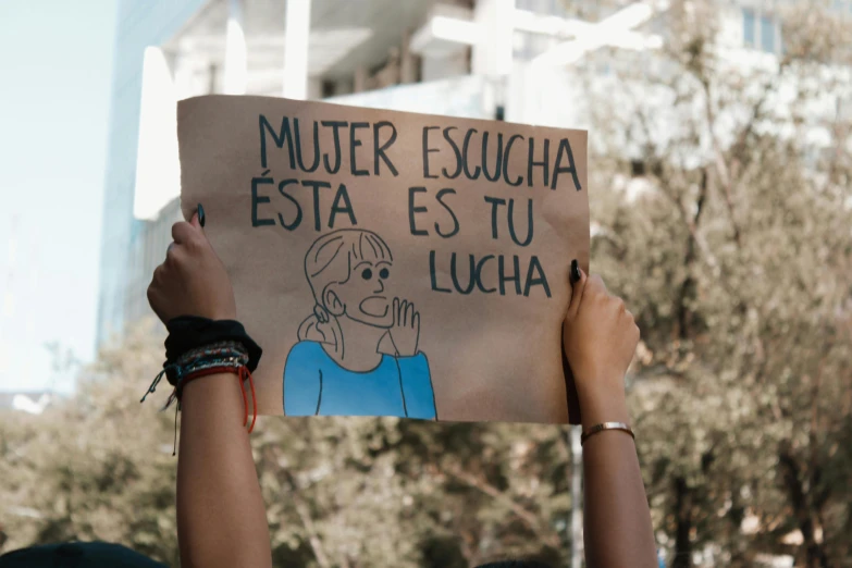 someone holding a sign that reads mueter escucha est est tu lucia
