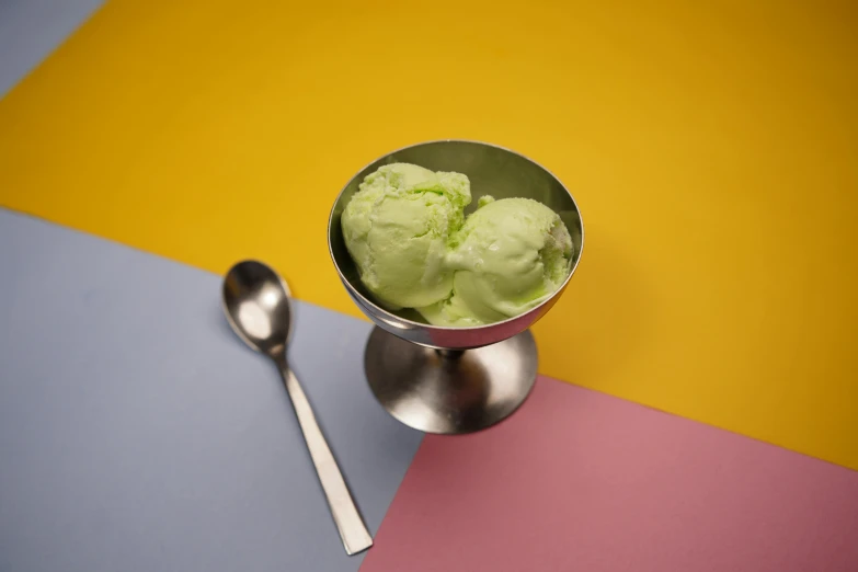 a scoop of ice cream in a silver bowl with spoon next to it