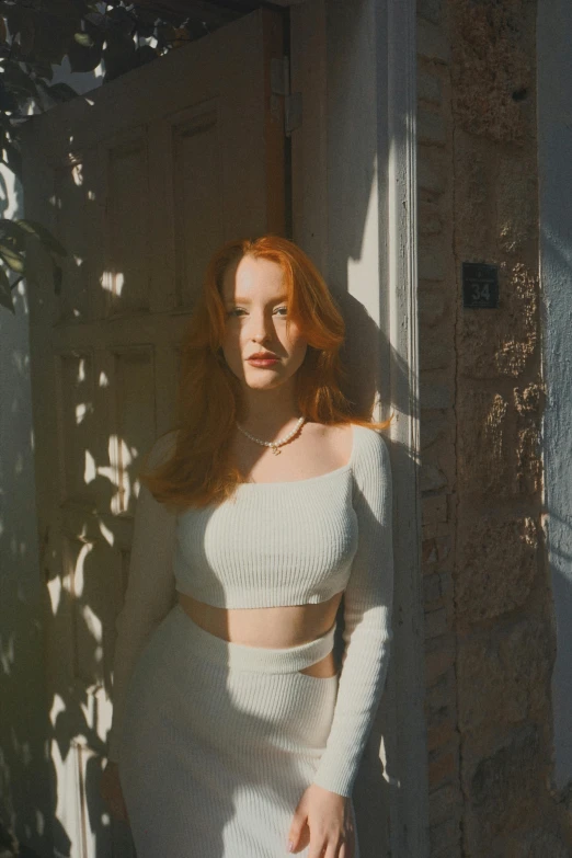 a woman standing in front of a doorway wearing a skirt and off white sweater